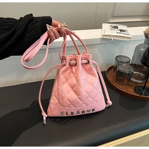 Close-up of pink quilted bucket bag with Clear K metal logo and drawstring closure