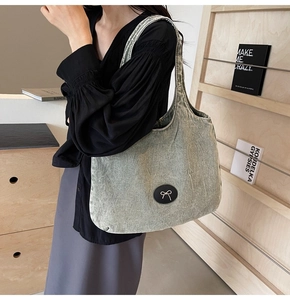Détail du grand sac cabas en denim vert rétro avec écusson nœud noir et bandoulière large