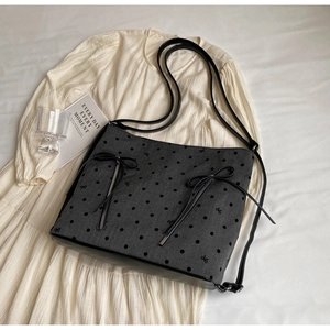 Close-up of dark grey tote bag with polka dots, bow embroidery and leather base details