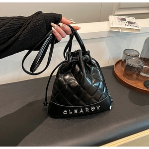 Detail of black quilted bucket bag with rhinestone CLEAROK lettering and drawstring closure