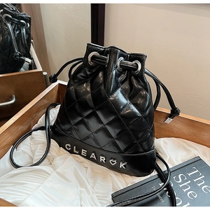Detail of black quilted bucket backpack with drawstring and silver metal logo lettering