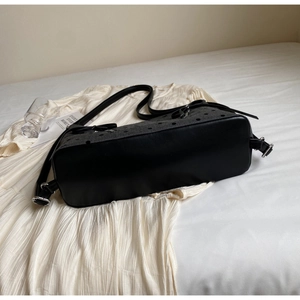 Detailed view of the black leather base and grey polka dot canvas on the tote bag