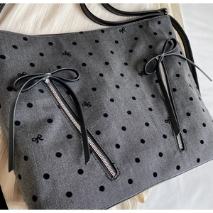 Detail of grey herringbone fabric with black polka dots and silver zipper accents