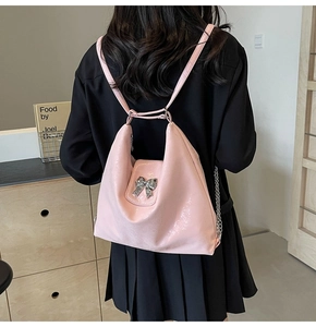 Pink patent hobo bag with silver bow detail and chain strap shown on a model