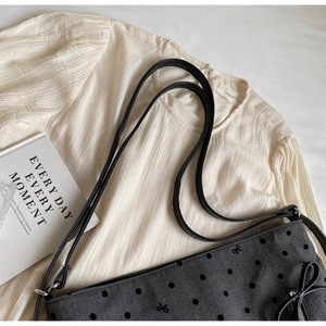 Detail of grey polka dot tote with bow embroidery and herringbone texture straps