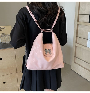 Detailed view of pink glossy backpack with elegant silver metal bow buckle and strap
