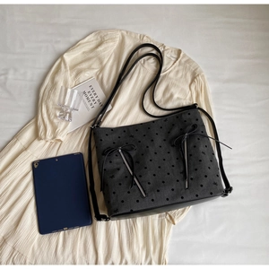 Detailed shot of dark grey tote with black polka dots and decorative bow zippers