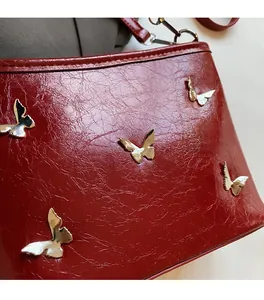 Close-up of deep red pleated leather texture with golden butterfly metal ornaments