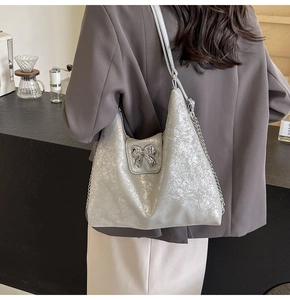 Silver glitter hobo shoulder bag with metal bow detail and chain strap on model