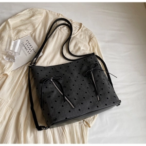 Detail of grey canvas tote featuring black polka dots and embroidered bow decorations