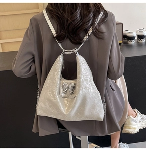 Detail of silver glitter tote bag with metallic bow and chain shoulder strap