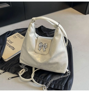 Detail of white pearlescent leather hobo bag with a silver metal bow buckle accent