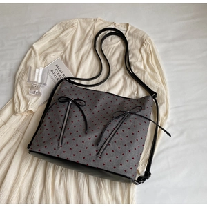 Detail of grey tote bag with red heart print, leather straps and bow zip decoration