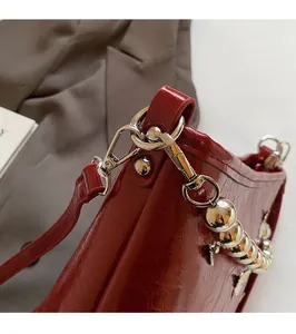 Close-up of glossy red patent leather shoulder bag with silver metallic hardware detail