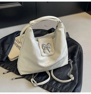 Detail of a cream tote bag with marble texture and silver metal bow ornament buckle