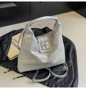 Detail of silver hobo bag with cracked texture and metallic silver bow decoration