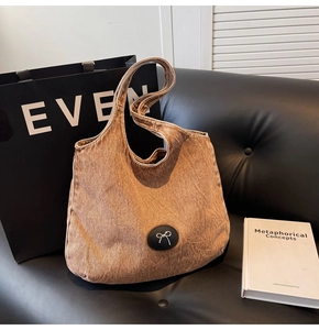 Détail d'un grand sac cabas en denim marron avec un écusson noeud minimaliste