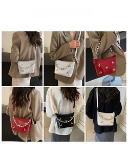 Detail view of crossbody bucket bags in silver and red with pearl butterfly chains