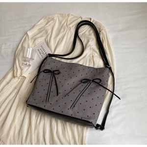 Detail view of gray canvas tote with red polka dots, black bows and front zippers