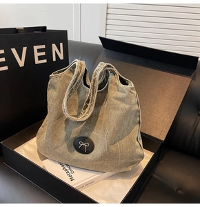 Gros plan du sac cabas en denim vert armée avec étiquette nœud argenté en coffret