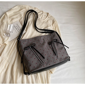 Detail of grey polka dot tote bag with metal zippers and black leather bow accents