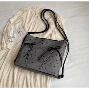 Detail of grey canvas tote with black star patterns and bow-tie zipper accents