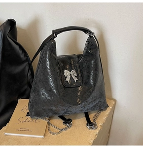 Close-up of retro black matte tote bag featuring silver bow metal buckle and chain strap