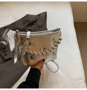 Detail view of silver crossbody bucket bag with 3D butterfly ornaments and bead handle
