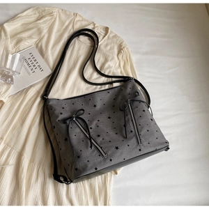 Close-up of star print canvas tote bag with black bow details and leather straps