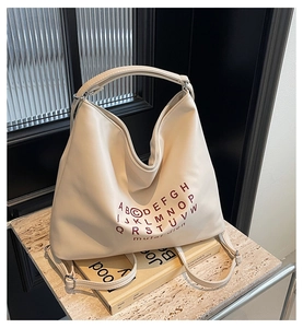 Detailed view of cream PU leather tote bag with red alphabet print and versatile straps