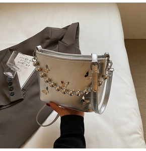 Detailed view of silver bucket bag with butterfly accents and metallic ball chain
