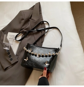 Close-up of black crossbody bucket bag with silver butterfly charms and beaded chain detail