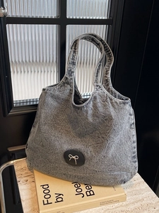Grand sac cabas en denim délavé gris avec nœud métallique sur table en marbre