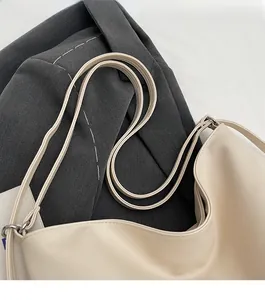 Detail of reinforced comfortable shoulder straps and metal rings on a cream hobo tote bag