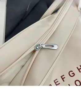Close-up of smooth silver metal zipper and red lettering on the beige fabric bag