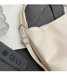 Detail of cream white leather shoulder bag with polished silver metal buckle and stitching