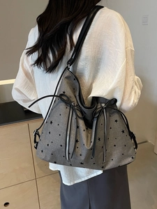 Grey canvas tote bag with star pattern and silver zippers shown in a lifestyle setting