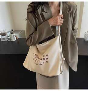 Lifestyle view of large cream leather tote bag with brown typographic print on model