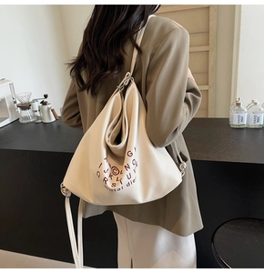 Detail of beige large capacity PU leather tote bag with red letter pattern and wide strap