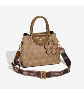 Close-up of brown bucket bag with horse print, wide logo strap, and floral charm detail