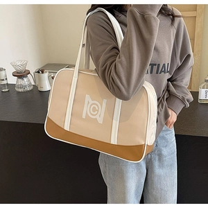 Detail of a large beige and tan tote bag with a white geometric logo in a cafe setting
