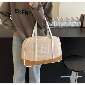Detail of a large beige tote bag with brown leather bottom and white geometric logo