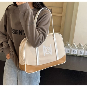 Detail of a large capacity cream tote bag with brown leather trim and geometric logo