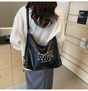 Close-up of black leather tote bag with white alphabet print and minimalist design