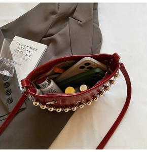 Macro view of red glossy crescent bag showing spacious interior and silver bead trim