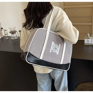 Side view of large grey tote bag with white leather straps shown on model in cafe