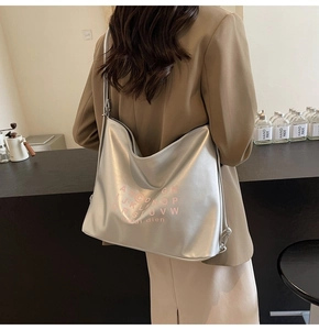 Detail of silver metallic hobo bag featuring pink letter print and adjustable shoulder strap