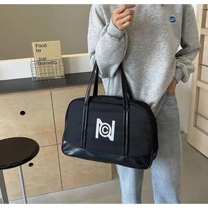 Detail of a large black nylon tote bag with leather handles and white logo for travel