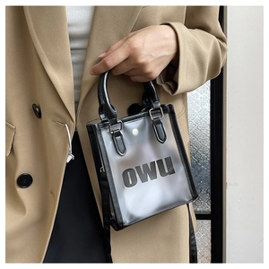 Detail of transparent PVC jelly tote bag with black leather handles and printed OWU logo