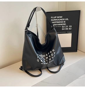 Close-up of black leather dual-use backpack featuring white letter print and metal buckles